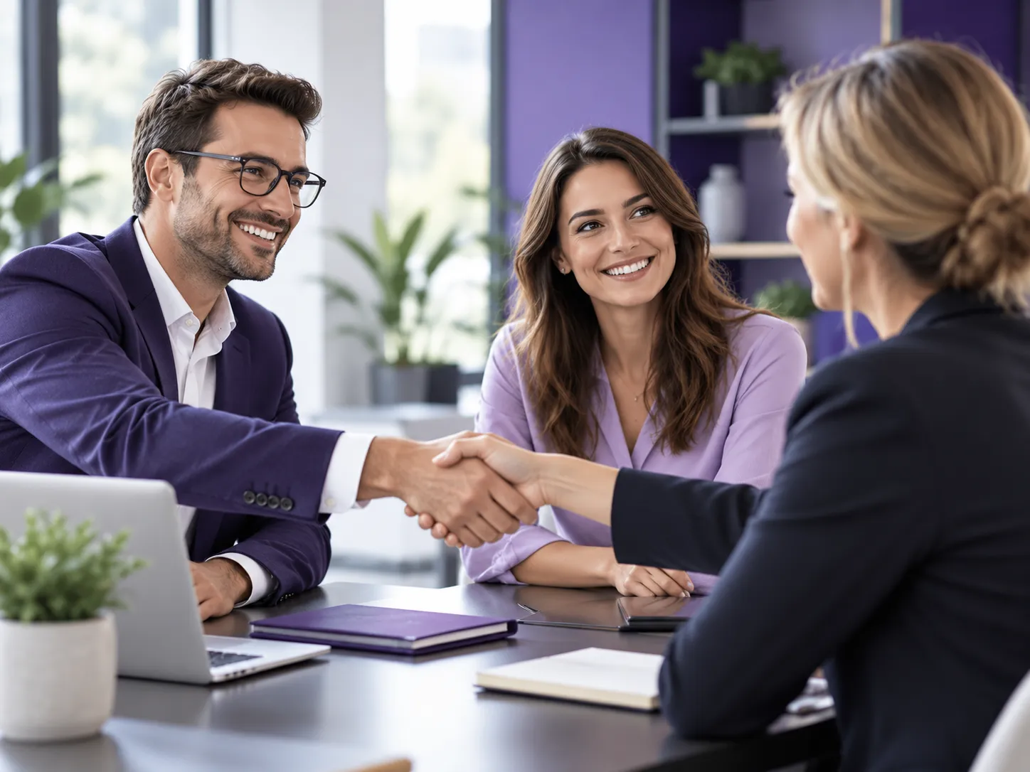 Drei Geschäftsleute besiegeln eine Partnerschaft mit einem Händedruck in einem modernen Büro mit violetten Akzenten und freundlicher Atmosphäre.